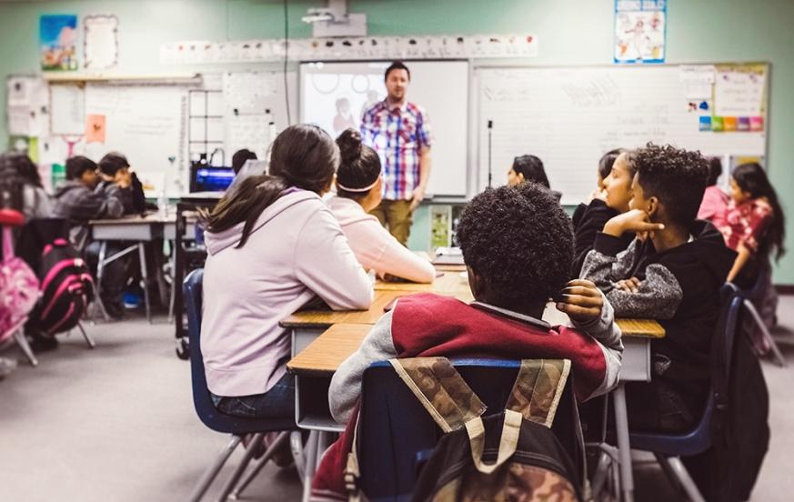 Paraprofessional to teacher student teaching in front of classroom